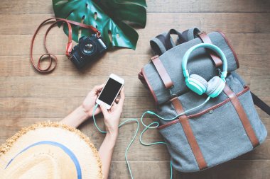 Sırt çantası, tatil seyahat kavramı üzerinde kulaklık ile akıllı telefon kullanan üstten görünüm turist kadın
