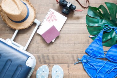 Yaratıcı düz yaz tatil kavramı ile bavul, pasaport, kamera ve bikini ahşap arka plan üzerinde göklere