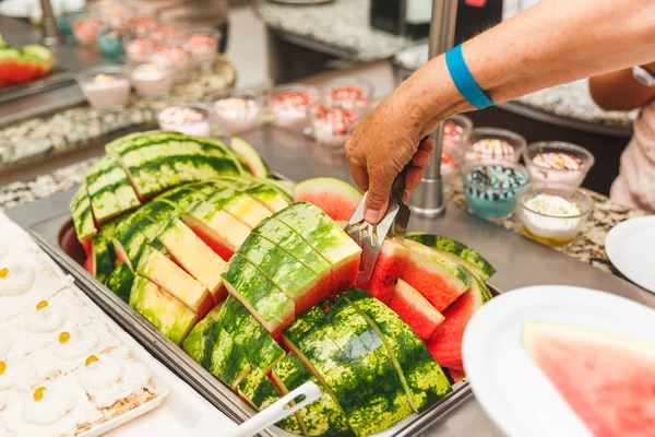 An elderly woman puts a plate of slices of ripe watermelon — Stock Photo, Image