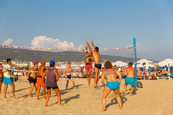 Adulti attivi praticano lo sport della pallavolo sulla spiaggia di sabbia — Foto Stock