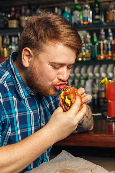 Junger Mann isst einen Hamburger — Stockfoto