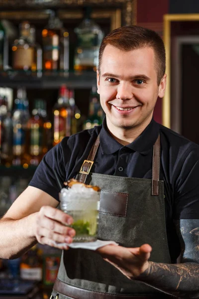 Cheerful bartender gives the cocktail to customer. — Stock Photo, Image