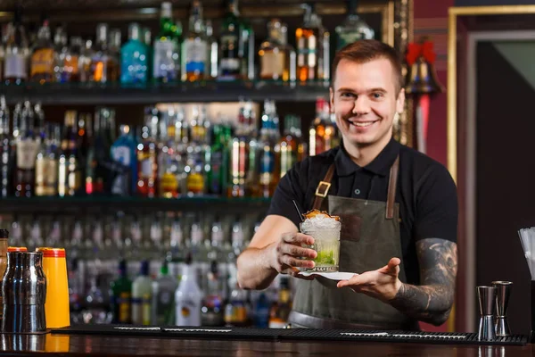 Cheerful bartender gives the cocktail to customer. — Stock Photo, Image