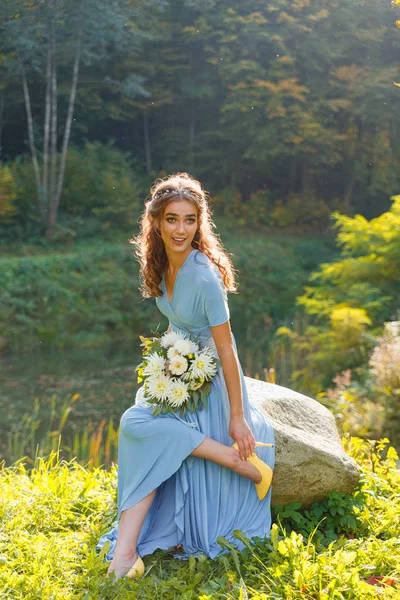 Красивая подружка невесты сидит на камне — стоковое фото