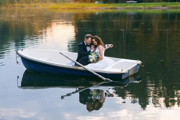 Bruden och brudgummen i en roddbåt på sjön — Stockfoto