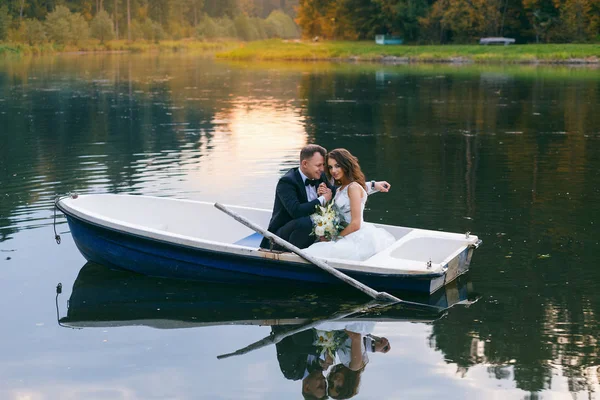 A noiva e o noivo em um barco a remos no lago — Fotografia de Stock