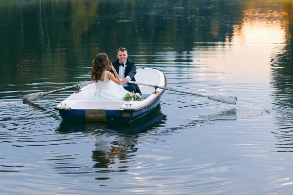 De bruid en bruidegom in een roeiboot op het meer — Stockfoto