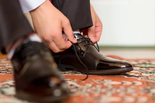 Jurken en bindt schoenen van de bruidegom — Stockfoto