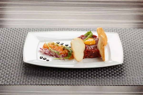 Изысканный тартар, поджаренный хлеб и салат на тарелке . — стоковое фото