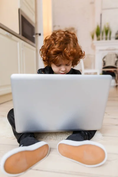 Piccolo ragazzo rossa utilizza un computer portatile — Foto Stock