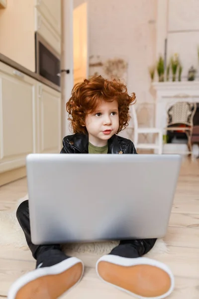 Piccolo ragazzo rossa utilizza un computer portatile — Foto Stock