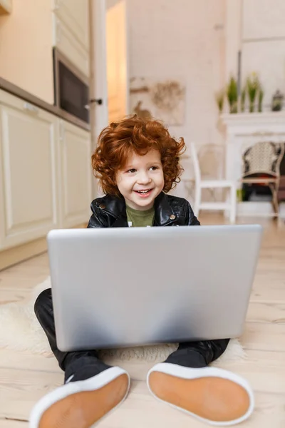 Piccolo ragazzo rossa utilizza un computer portatile — Foto Stock