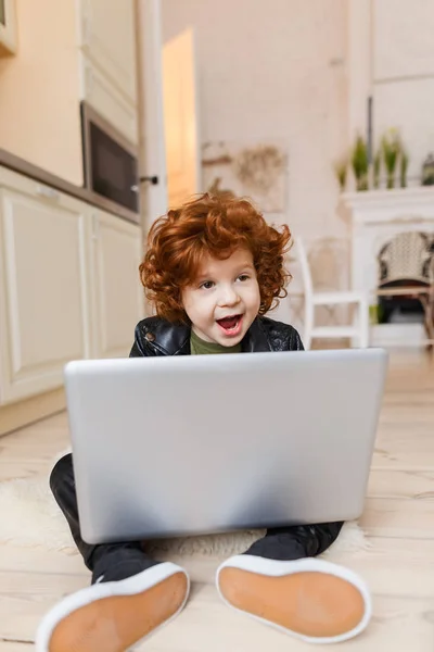 Pequeno menino ruivo usa um laptop — Fotografia de Stock