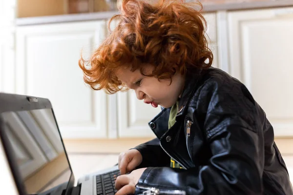 Pequeno menino ruivo usa um laptop — Fotografia de Stock