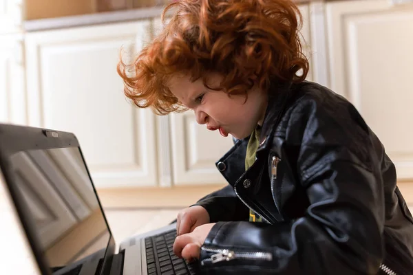 Pequeno menino ruivo usa um laptop — Fotografia de Stock