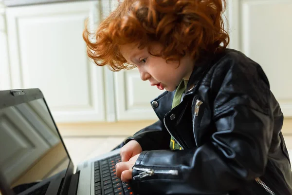 Pequeno menino ruivo usa um laptop — Fotografia de Stock