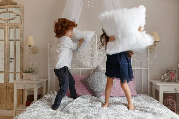 Kleine kinderen, jongen en meisje vechten met kussens — Stockfoto