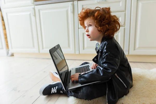 Little redhead boy uses a laptop — Stock Photo, Image