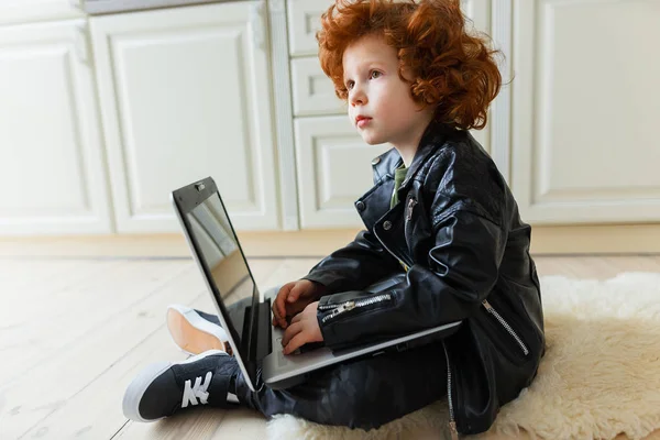 En liten rødhåret gutt bruker en bærbar pc – stockfoto