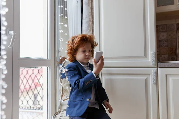 Little redhead boy uses a smartphone — Stock Photo, Image