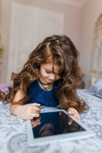 Cute little girl with curly hair using digital tablet — Stock Photo, Image
