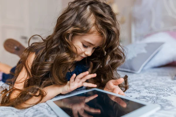 Симпатична маленька дівчинка з кучерявим волоссям за допомогою цифрового планшета — стокове фото