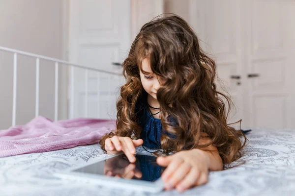 Το χαριτωμένο μικρό κορίτσι με σγουρά μαλλιά χρησιμοποιώντας ψηφιακό tablet — Φωτογραφία Αρχείου