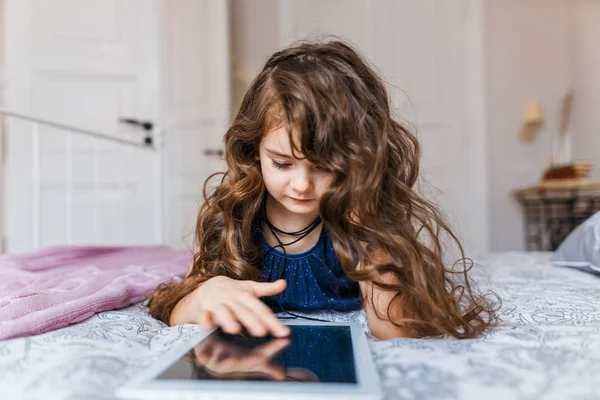 Το χαριτωμένο μικρό κορίτσι με σγουρά μαλλιά χρησιμοποιώντας ψηφιακό tablet — Φωτογραφία Αρχείου