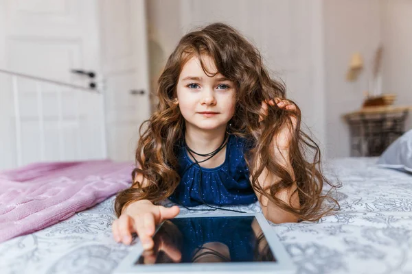 Симпатична маленька дівчинка з кучерявим волоссям за допомогою цифрового планшета — стокове фото