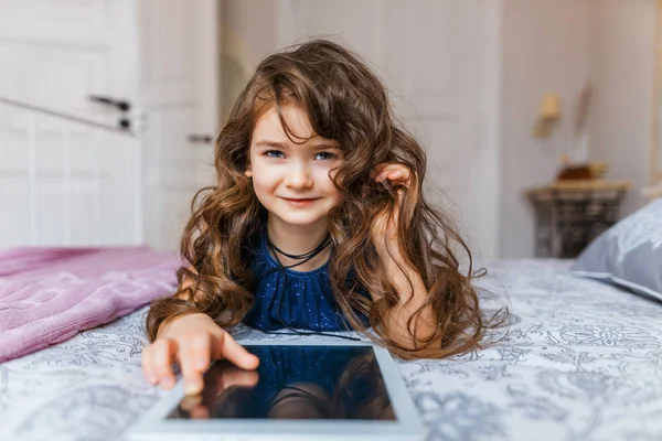 Cute little girl with curly hair using digital tablet — Stock Photo, Image