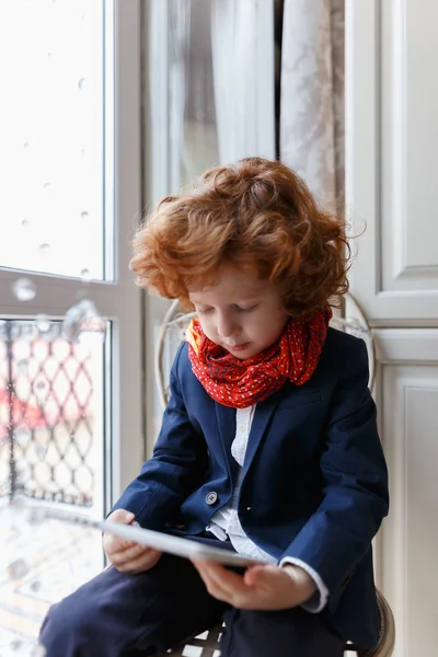 Liten rödhårig pojke använder en tablet Pc — Stockfoto