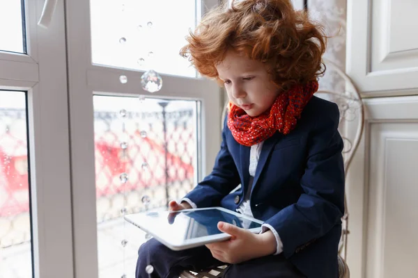 Little redhead boy uses a tablet PC — Stock Photo, Image