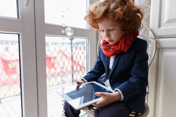 Маленький рыжий мальчик пользуется планшетным ПК — стоковое фото