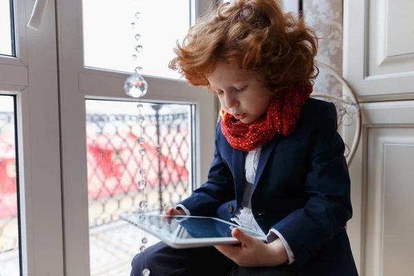 Little redhead boy uses a tablet PC — Stock Photo, Image