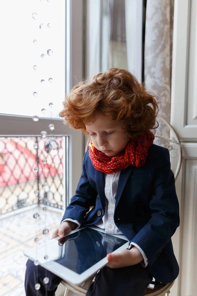 Little redhead boy uses a tablet PC — Stock Photo, Image