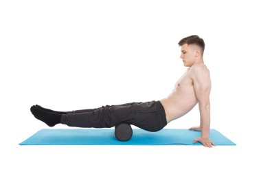 Yakışıklı adam, tetikleyici noktaların miyofasyal masajı için köpük silindiri kullanarak egzersiz yapıyor. Arka kalça kaslarına masaj. Beyazda izole edilmiş.