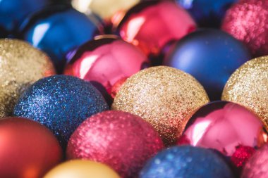 Mavi, kırmızı, pembe ve altın sarısı parlak ve parıltılı Noel süsleri.