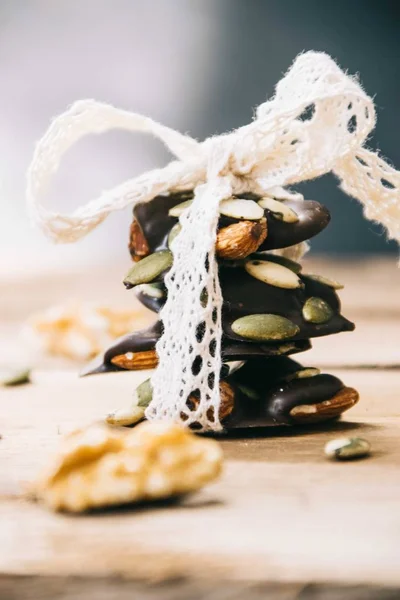 Close up of a pack of healthy snacks made from almonds, walnuts, hazelnuts and pumpkin seeds tied up with white lace on a wooden base — Stock Photo, Image