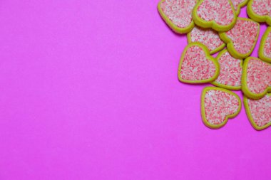 Pembe fuşya arka planında pembe şekerli kalp şeklinde kurabiyeler. Aşk konsepti