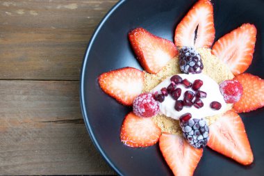 Dilimlenmiş çilekleri kurabiye parçacıkları, krem şanti, nar tohumları, böğürtlen ve ahududu ile kaplayın.