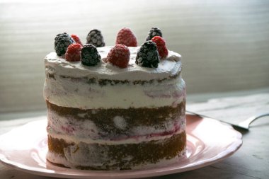 Krem şanti ve böğürtlen sosuyla dolu sünger keki. Üstünde ahududu ve böğürtlen var. Çıplak pasta konsepti