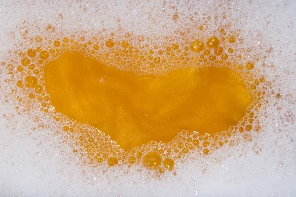 wallpaper of soap foam and orange water with golden sparkles. Copy space concept.