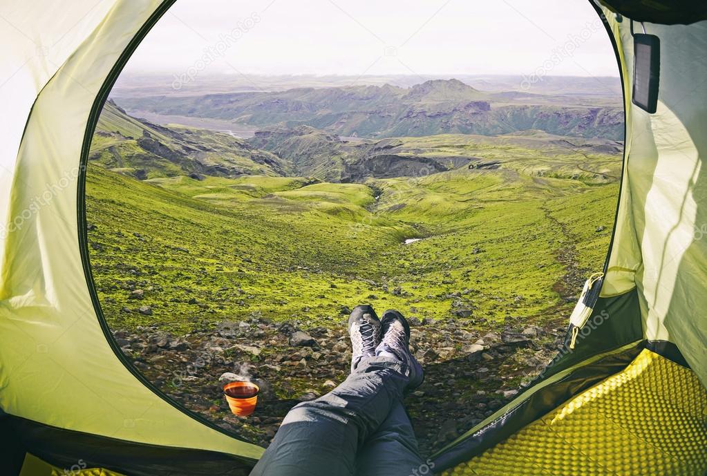 Woman lying in tent with a view of mountain  and valley in Iceland 