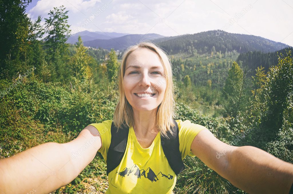 Smiling  woman takes a selfie  on mountain peak in Carpathian Mountains 