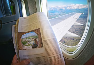 Kadın pencere elinde dergisi ile bir uçakta oturuyor. 