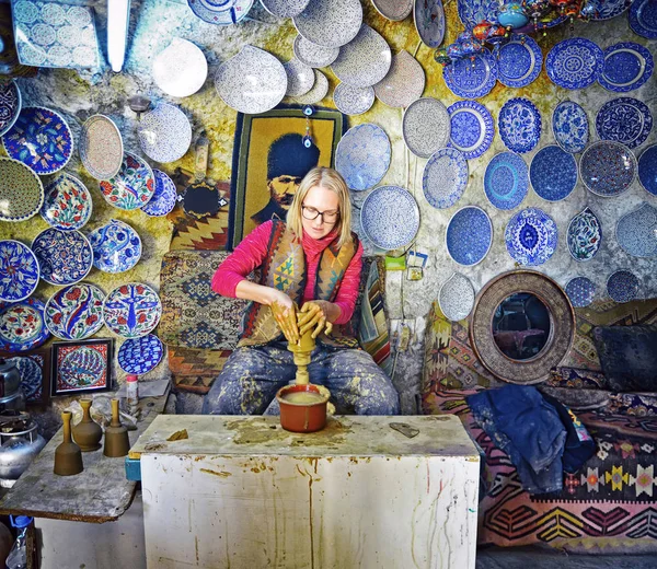 Woman working on the potter's wheel, making the dishes with their own hands
