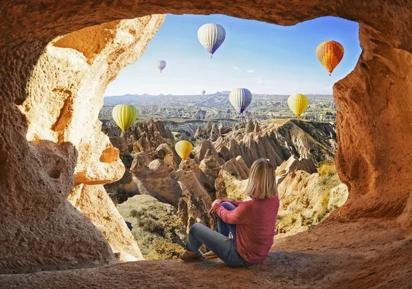 Kvinnan tittar som färgglada Luftballonger flyger över dalen på Cappadocia — Stockfoto