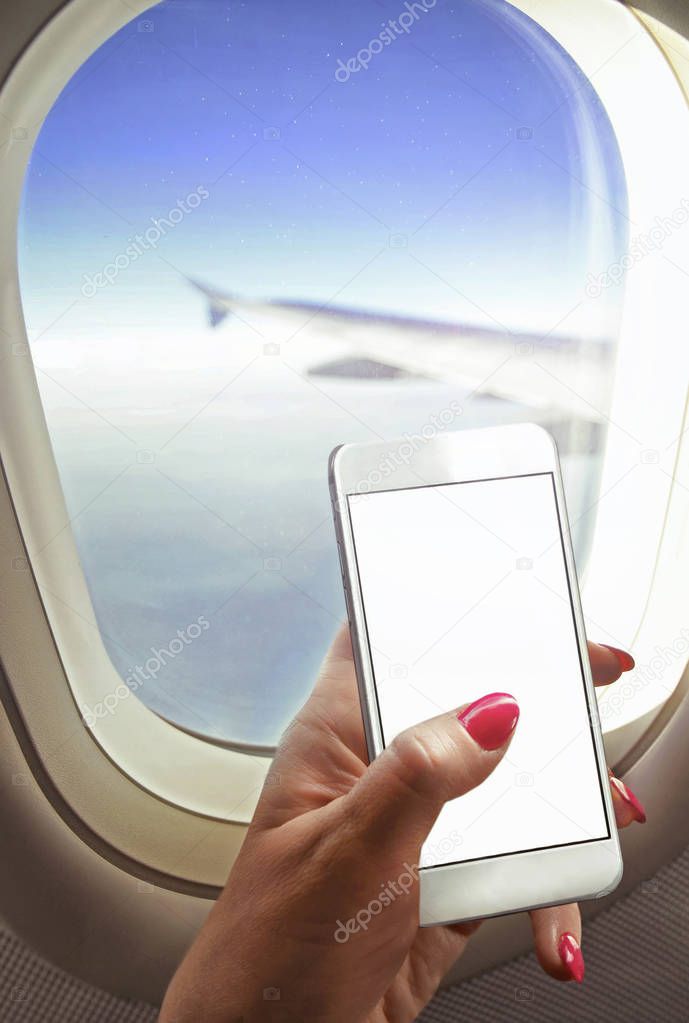 Woman  sit near window , holding smart-phone working on board of airplane