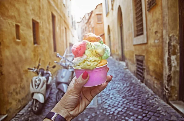 Italian ice - cream cone held in hand on the background of on vintage street atmosphere — Stock Photo, Image