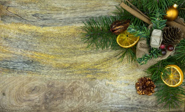 Tablero de madera con ramas de abeto, naranjas secas y palitos de canela — Foto de Stock